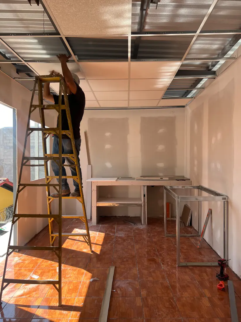 Operario instalando cielo suspendido de losetas sobre estructura metálica