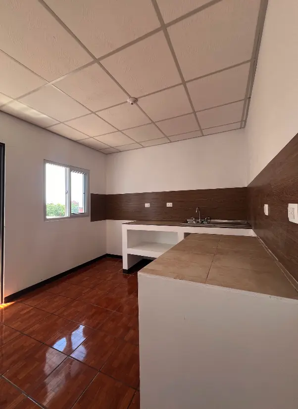 Cocina terminada con mesón enchapado, salpicadera tipo madera y cielo suspendido