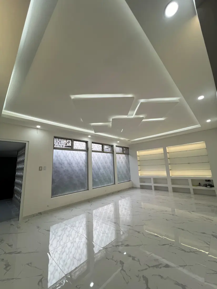 Salón terminado con cielo falso flotante, iluminación LED y repisas iluminadas