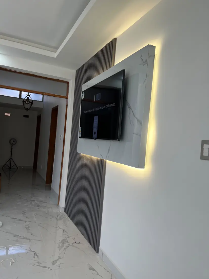 Muro de TV con panel tipo mármol retroiluminado y listones decorativos